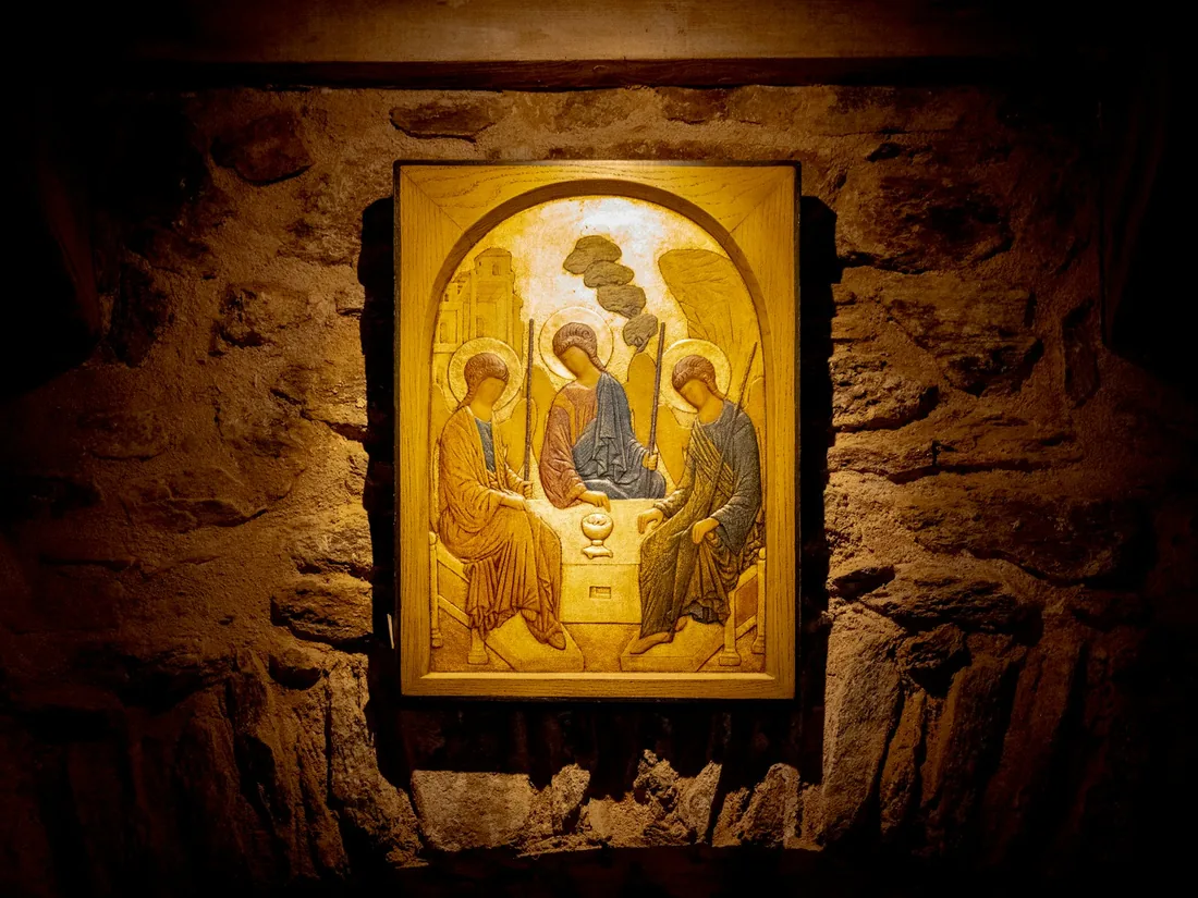 Tabla de icono con marco tallado y fondo dorado, iluminada sobre un muro de piedra